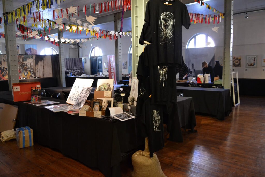 Open Book Comics Fest 2017 table set-up with hand-painted T-Shirts to the right of the table